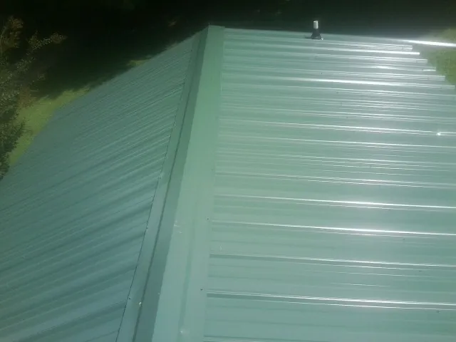 New green metal panels meeting at the ridge of a roof — Flat Roof Repair work by our crew in Lambertville