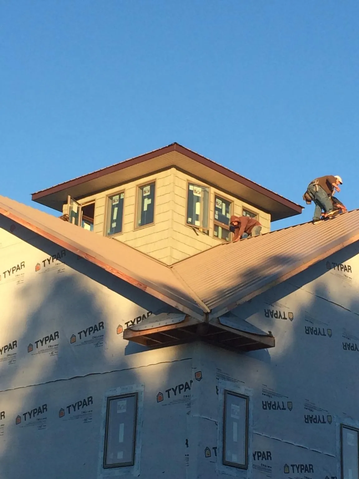 Roofers working around a rooftop cupola on a new metal roof at sunset — Roof Waterproofing in Lambertville by Roofing Brothers